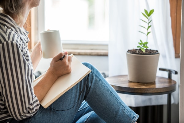 Woman with a cup of tea writing in a notebook